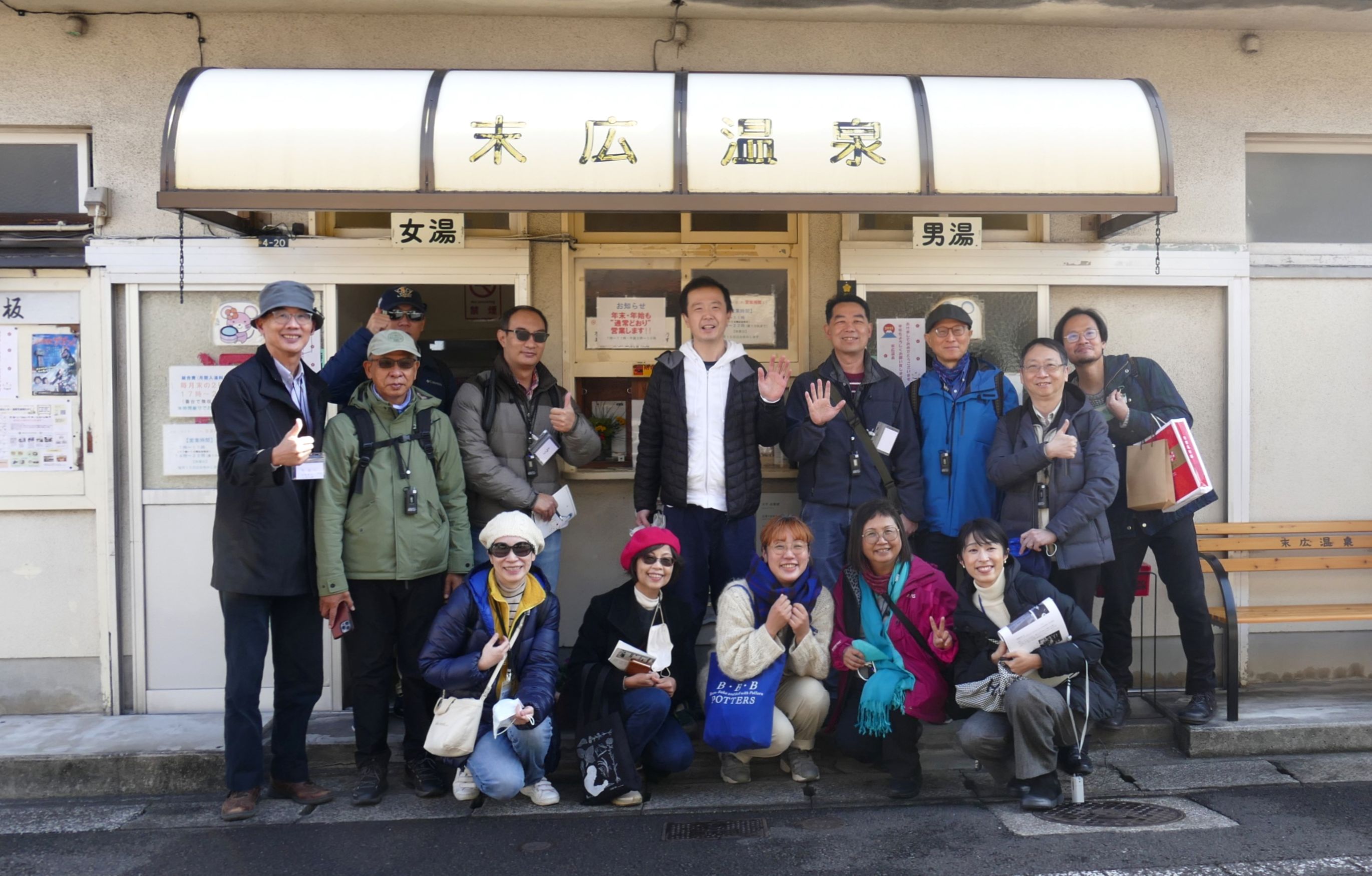 圖：藝術家勝正光（後排右五）帶領團員走訪別府街道。眾人身後的「末廣溫泉」是他擔任組合長的社區型溫泉設施，一樓為澡堂，二樓是社區的公民會館，也開放藝術家申請使用。