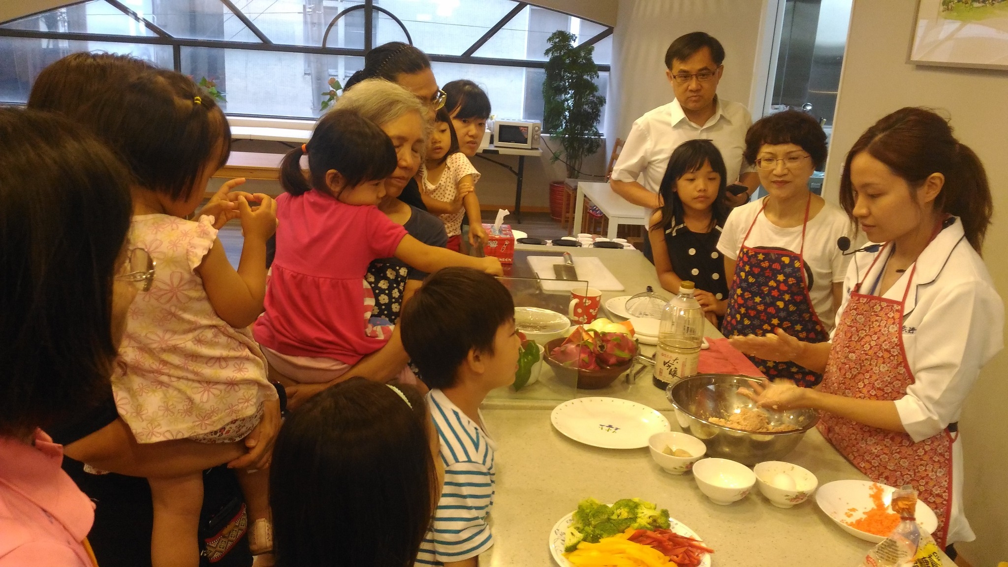 圖：親子食農市場小旅行活動中，由「陳宏麟診所」的營養師（右一）向參與者介紹每日餐盤營養指南，並在現場示範烹調方式，再由參與者試作料理。